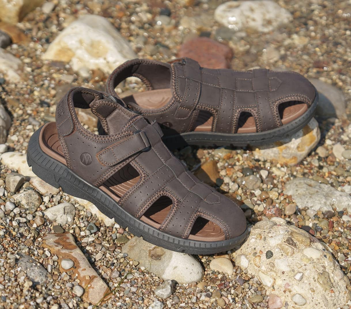 Shop Nunn Bush sandals featuring the Laguna fisherman sandal on a rocky beach.